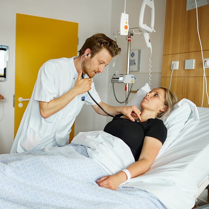 Verpleegkundige controleert hartslag patiënt.