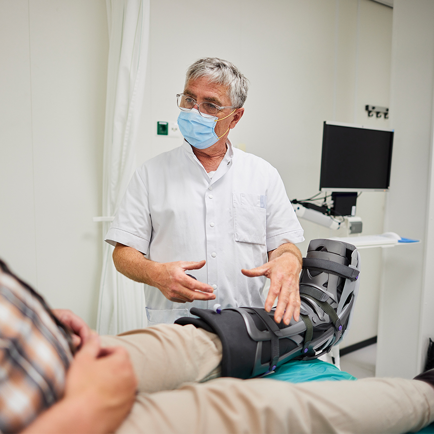Gipskamer Arts informeert patient over zijn nieuwe loopgips.