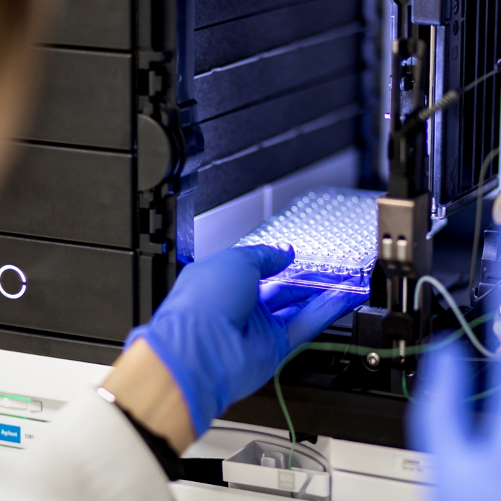Researcher places sample tray in lab device