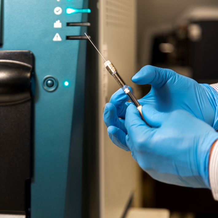 Close-up of researcher preparing syringe needle in lab