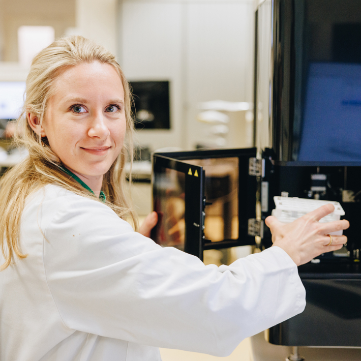 Researcher places a wellplate with samples in a piece of equipment at the FCF lab