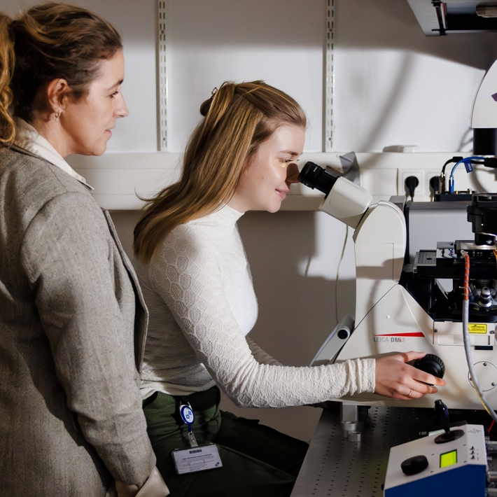 Trainer and trainee behind a confocal microscope