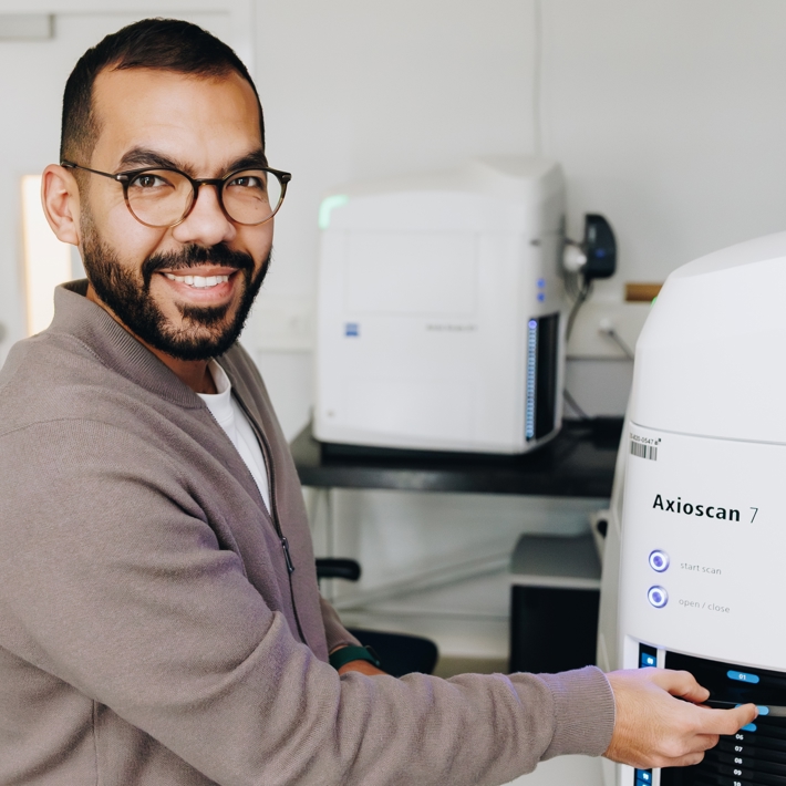 Person loading slides in slidescanner and smiling
