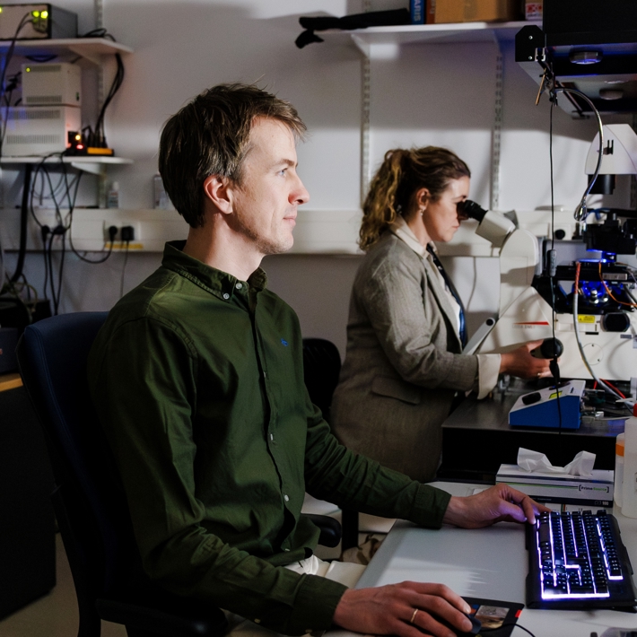 People operating confocal microscope and computer