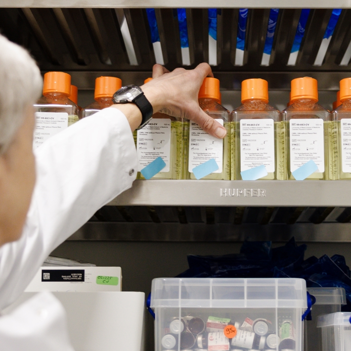 Person taking a bottle of medium from the cold room